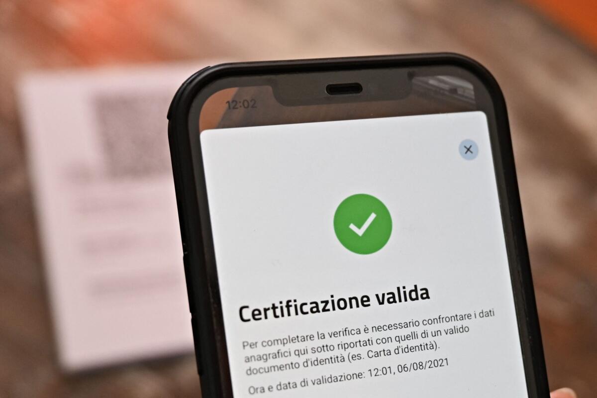 Misure anti Covid: il conto salato lo pagano sempre le stesse categorie - A bar owner shows a valid Green Pass on the VerifyC19 mobile phone application in central Rome on August 6, 2021, as Italy made the Green Pass, which is an extension of the EU's digital Covid certificate, required from today to enter cinemas, museums