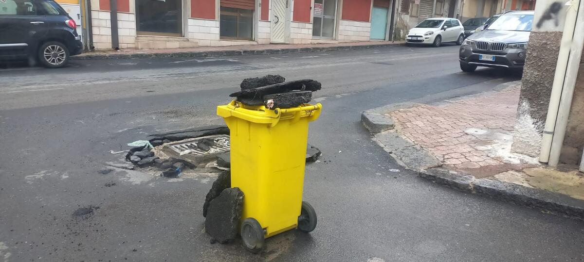 Contenitore dei rifiuti usato per segnalare un dissesto stradale - 